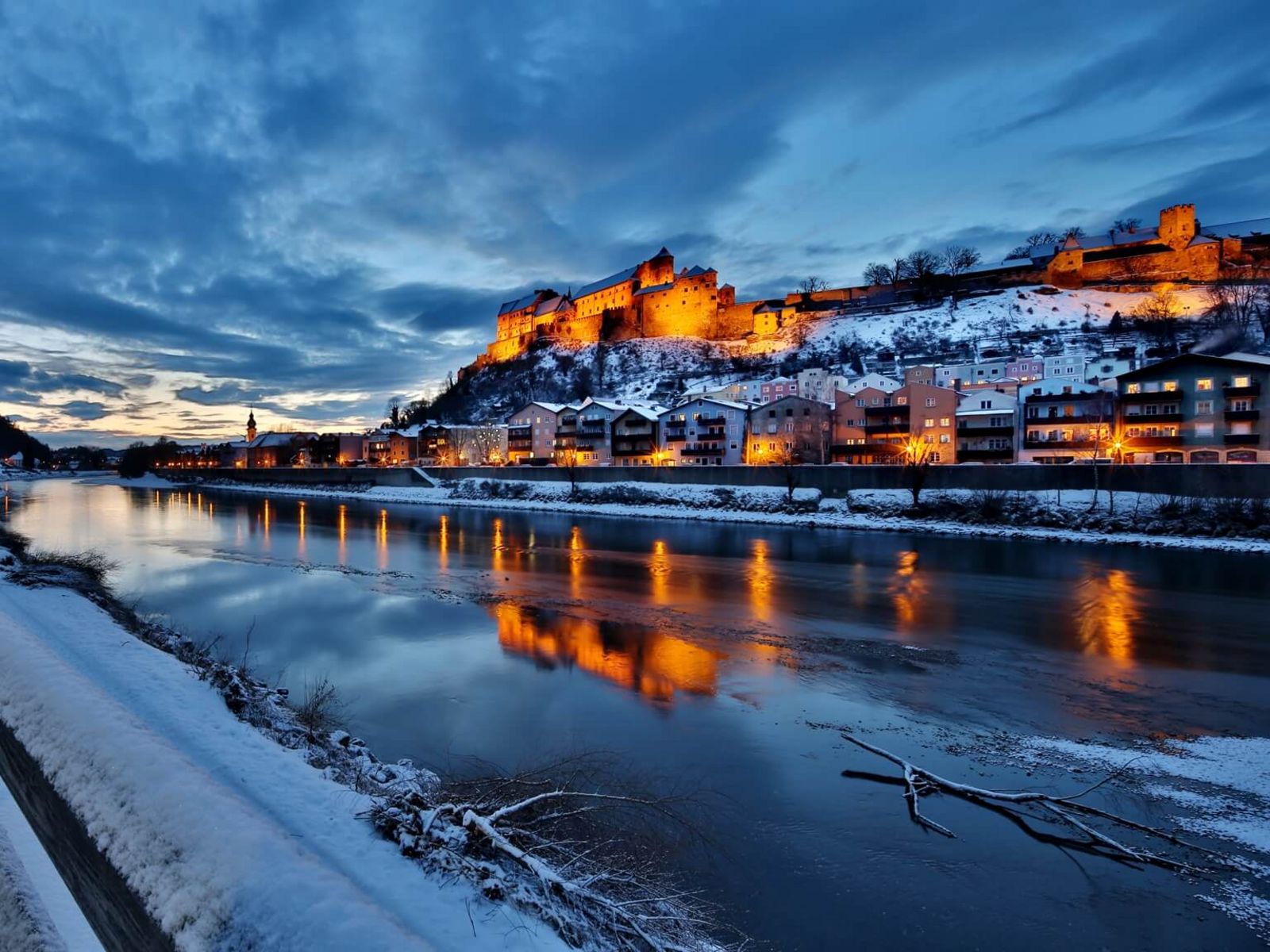 Burg und Lichter spiegeln sich in Salzach im Winter Dämmerung